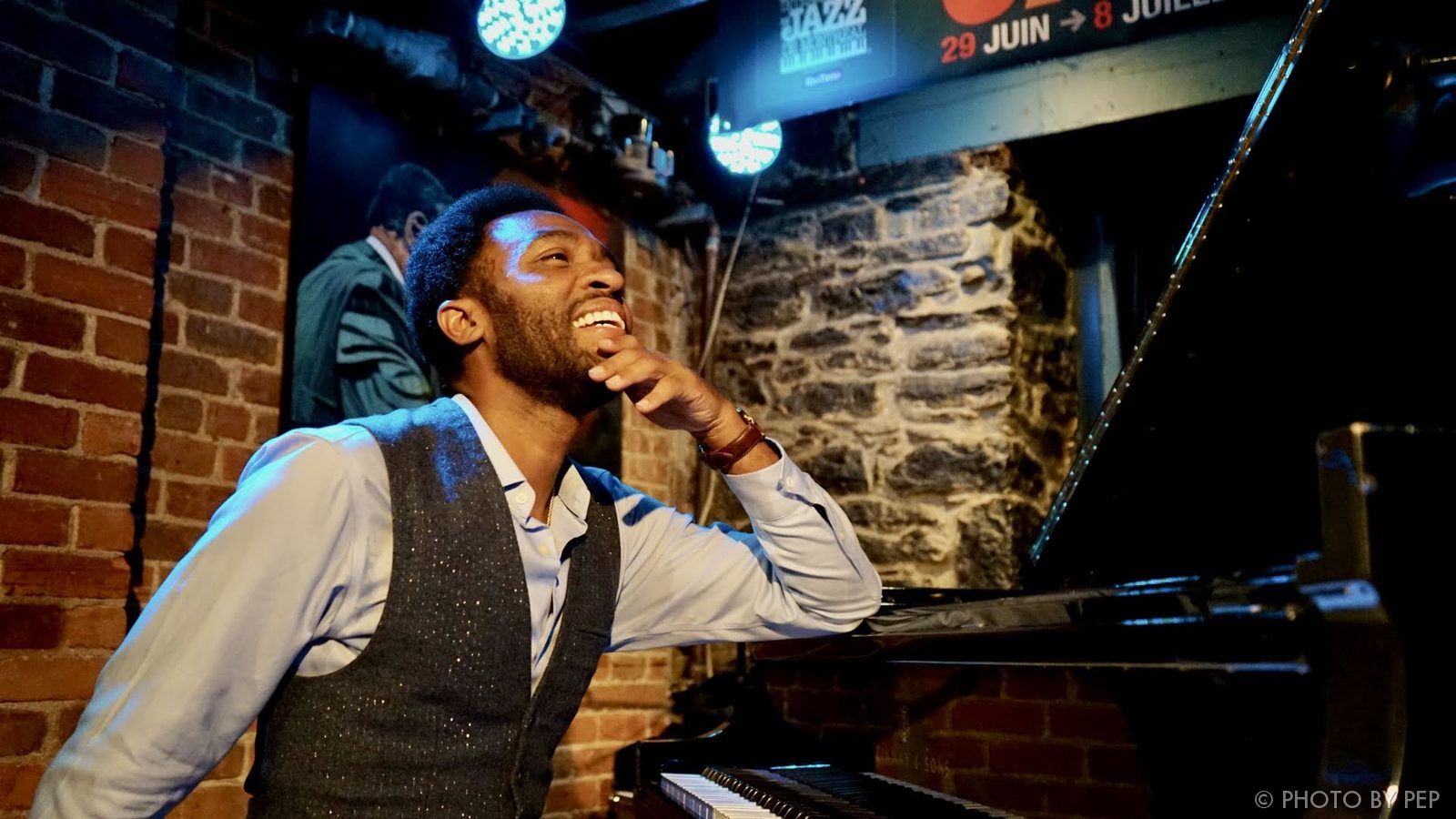 Smiling musician leaning on a grand piano at a jazz venue